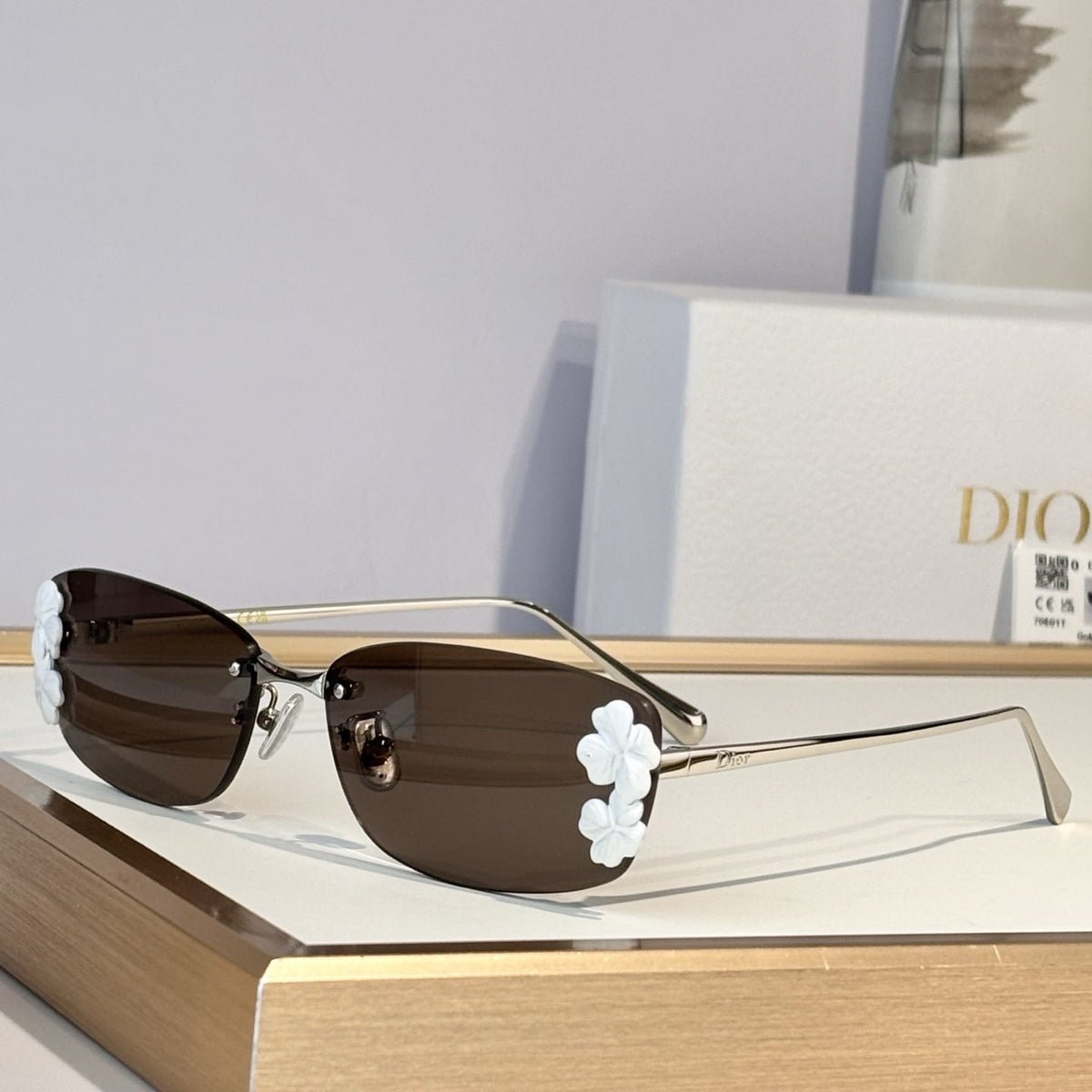 D**R Slim Rimless Oval Sunglasses with Warm Brown Solid Lenses, Silver Metal Temples & Sculptural White Flower Cluster Embellishment
